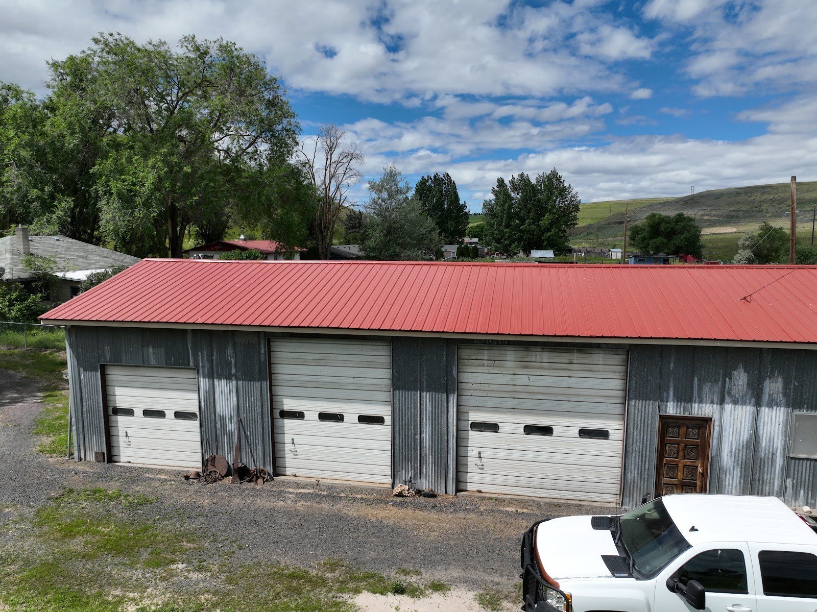 Red standing-seam metal roof on a three-bay shop building