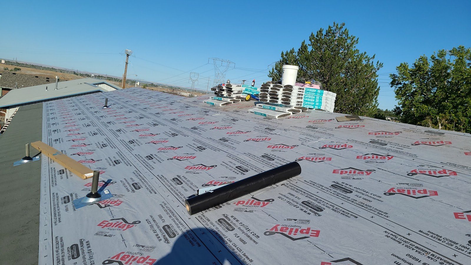 Synthetic underlayment rolled out on a roof deck before shingles go on